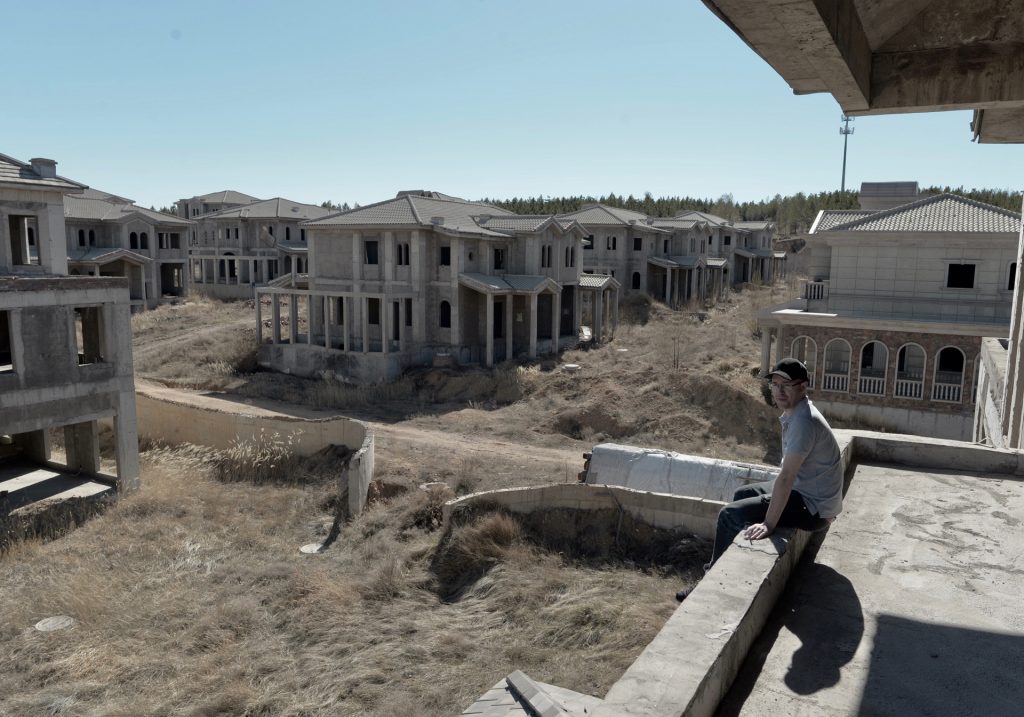 A man looks out over the empty buildings of Ordos Kangbashi in Inner Mongolia.