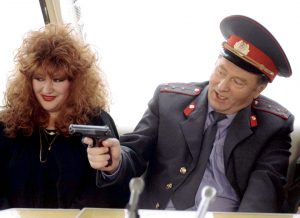 A police officer brandishing a firearm whilst a woman looks on in Transnistria.