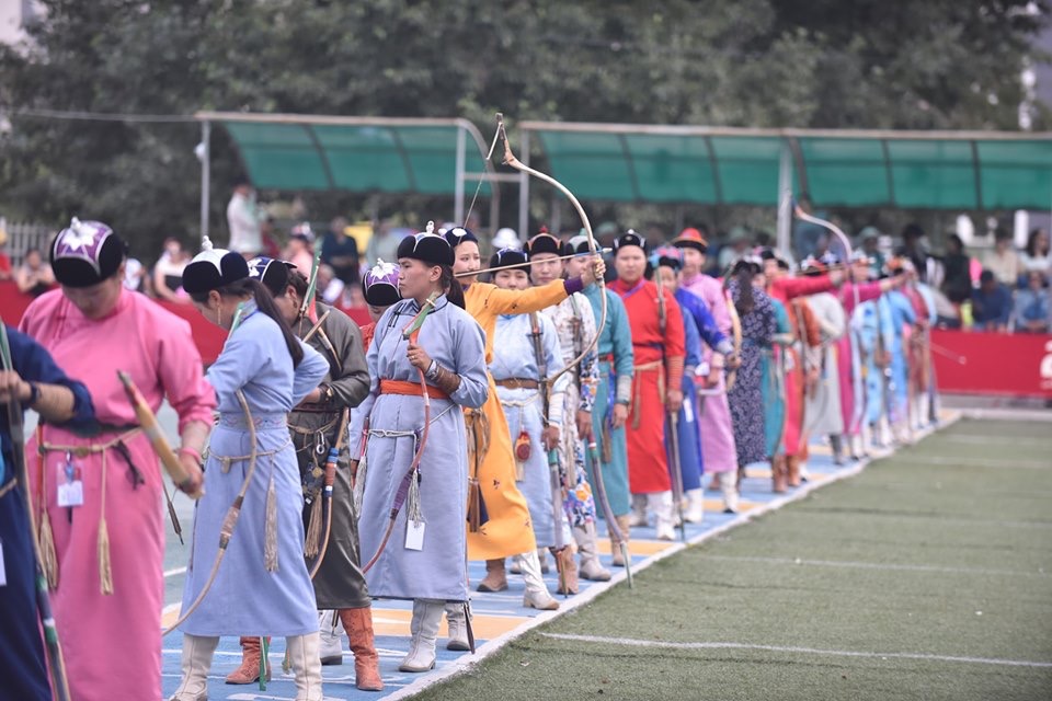 A line of women dressed in colourful traditional deels prepare to demonstrate their Mongolian archery skills at the Naadam archery competition.