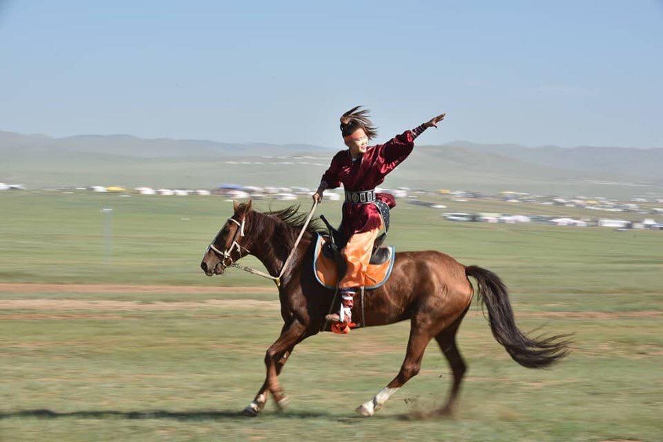 A rider strikes a pose whilst galloping in the run-up to a Mongol horse race.