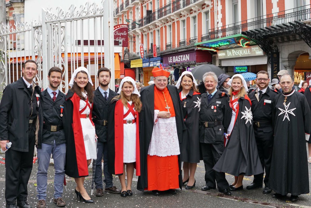 Dames and Knights of the Sovereign Military Order of Malta pose for a photo in the street.